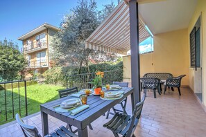A patio with a table set for dining, surrounded by chairs and a small garden area.