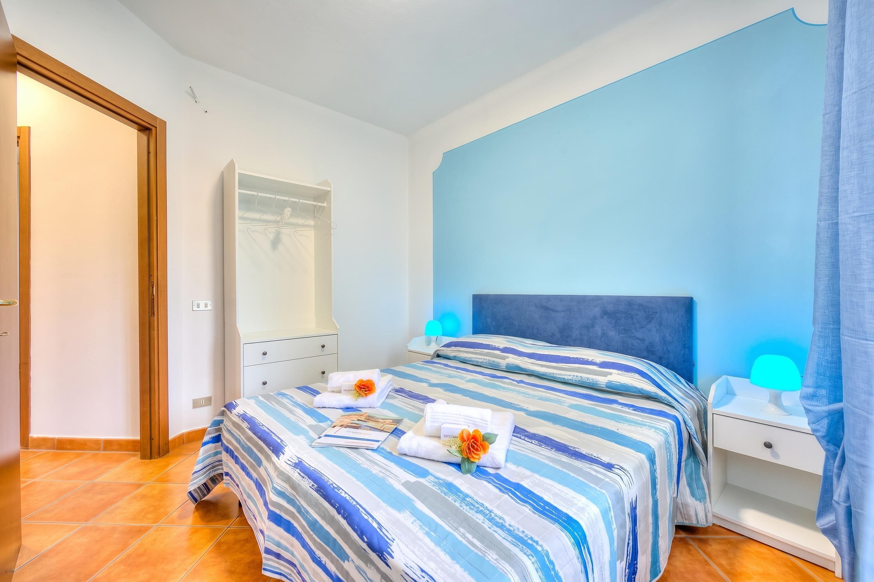 Ein Hotelzimmer mit Bett, Nachttisch, Spiegel und Tür.