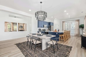 A modern kitchen with blue cabinets, a central island, and a dining area with a table and chairs.