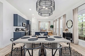 Una cocina moderna con armarios oscuros, una isla central y una zona de comedor con mesa y sillas.