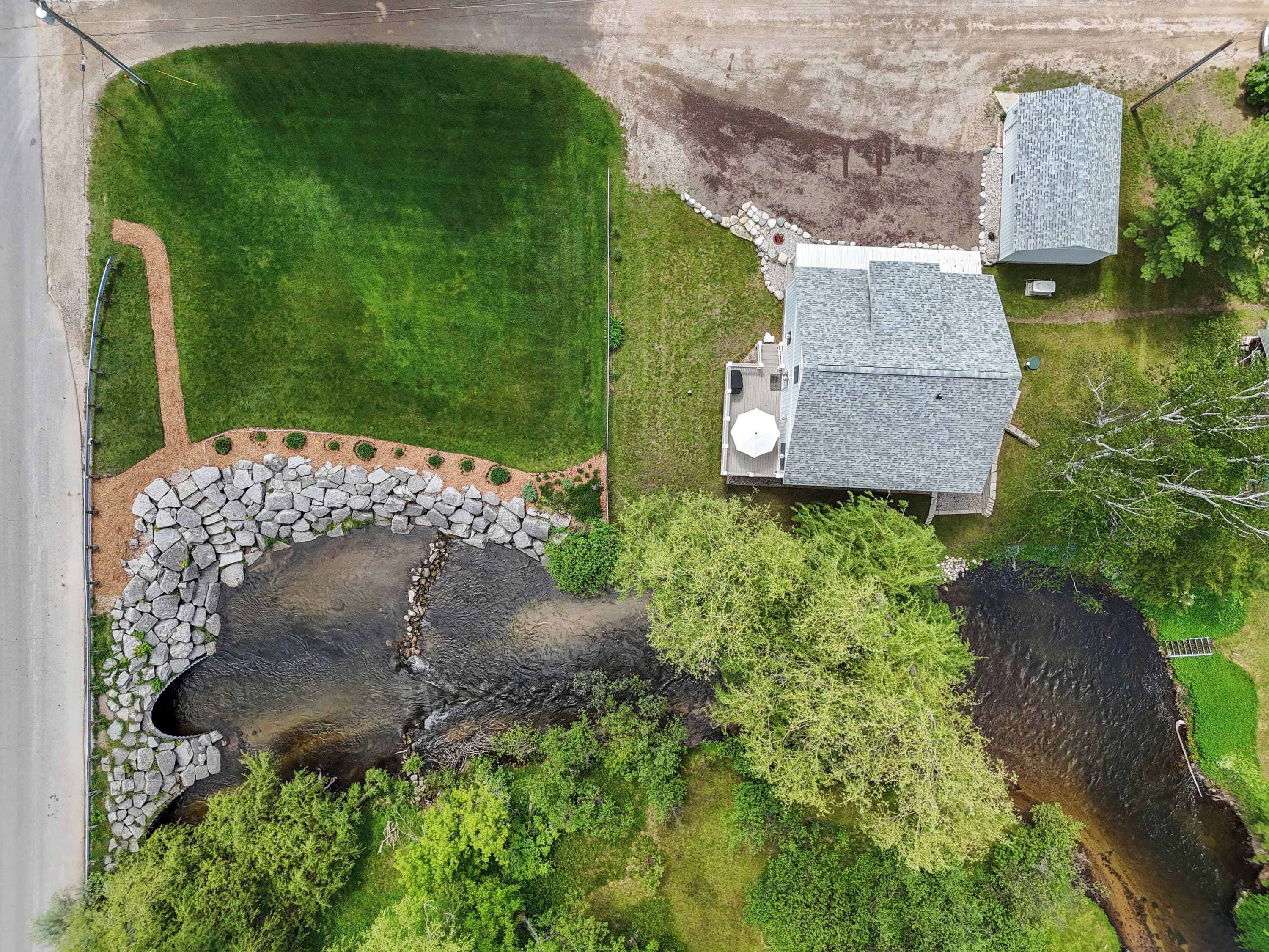 A large, open grassy area with a stone pathway leading to a small building with a sloped roof.