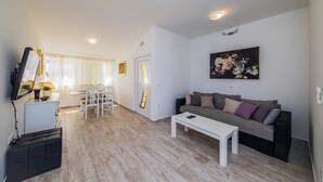 A modern living room with a white sofa, a coffee table, and a dining area with a table and chairs. - Raos in Trogir - Mittel-Dalmatien / Raos in Trogir - Appartement für 4-6 Personen (Trogir)