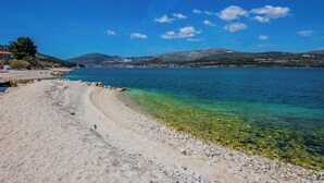 A beach with clear water, a pebble path, and distant hills. - Raos in Trogir - Mittel-Dalmatien / Raos in Trogir - Appartement für 4-6 Personen (Trogir)