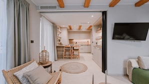 Una sala moderna con un sofá, una silla de mimbre, una mesita y un televisor montado en la pared.