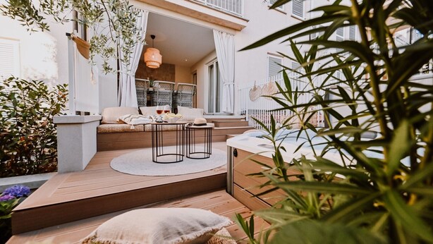 Una zona de estar al aire libre acogedora con un sofá, dos sillones y una mesita.