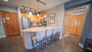 Una cocina moderna con una isla central, armarios de madera e iluminación colgante.