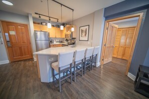 A modern kitchen with a central island, wooden cabinets, and pendant lighting. - Walk to River Run From this unit, Dining, Shopping (Keystone)