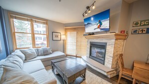 Una sala de estar moderna con chimenea, un televisor de pantalla plana grande y un área de descanso confortable.