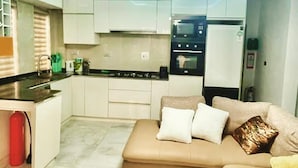 Cozinha moderna com armários brancos, forno embutido e geladeira.