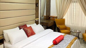 Quarto de hotel com cama, escrivaninha, cadeira e uma pequena mesa.