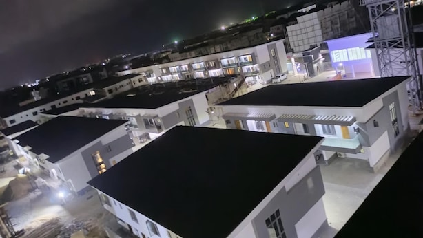 Vista noturna de uma área residencial com vários edifícios brancos, alguns com varandas e janelas visíveis.