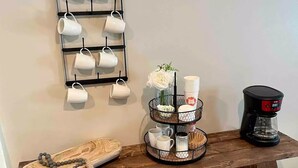 A wooden table with a coffee maker, a tray with cups and a vase of flowers, and a wall-mounted mug rack. - Stylish Richmond Home. Near EKU and Downtown (Richmond)
