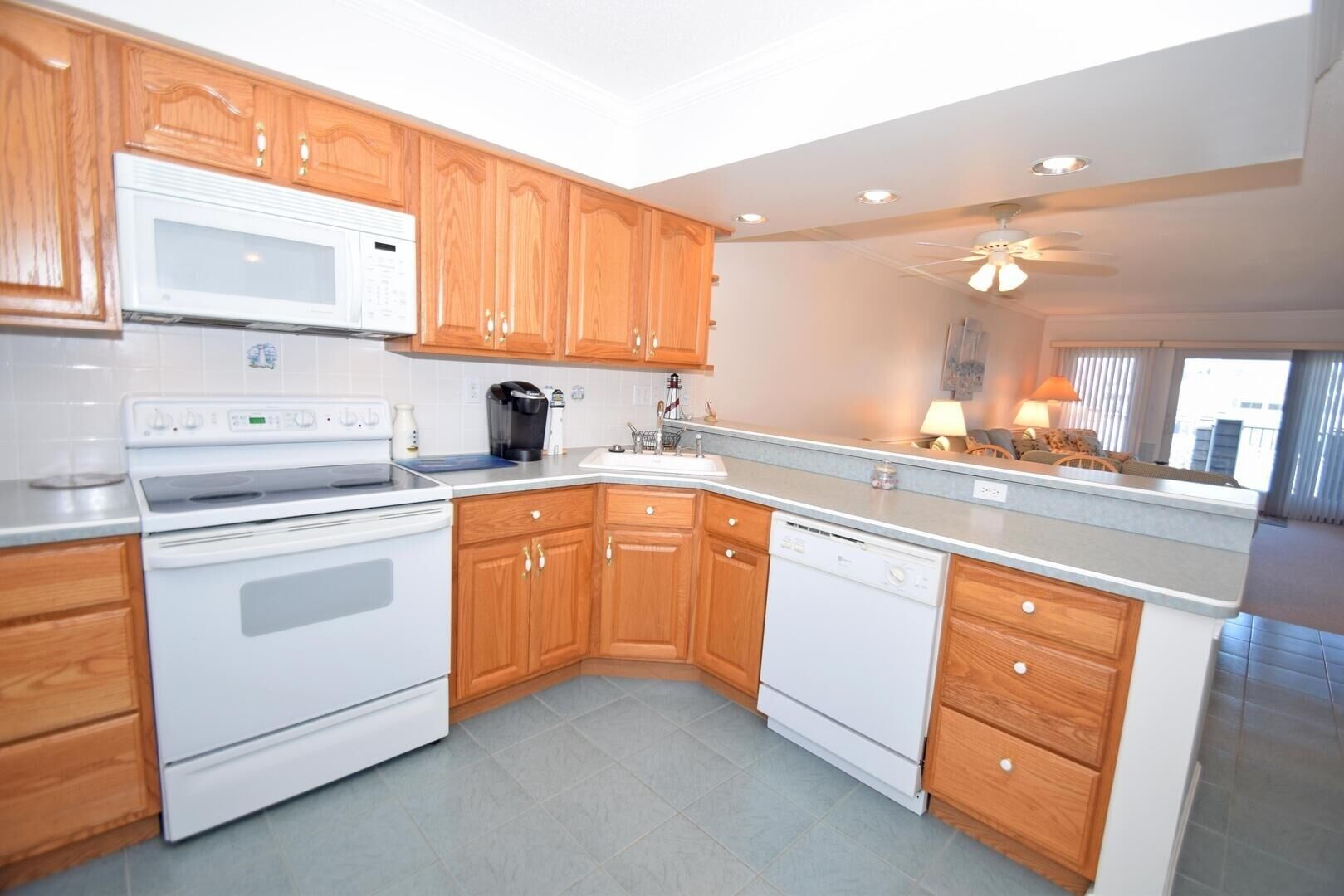 A modern kitchen with wooden cabinets, white appliances, and a grey countertop.