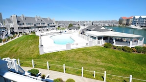 Ett bostadsområde med en swimmingpool, en inglasad veranda och en småbåtshamn i bakgrunden.