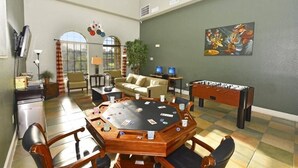 A spacious room with a round table for games, a foosball table, and comfortable seating.