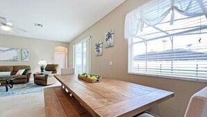 A spacious living room with a wooden dining table, a sofa set, and a large window with blinds. - Henley Haven 6 Bedroom Villa by RedAwning (Davenport)