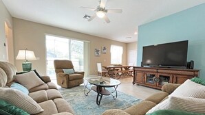 A living room with a sofa, armchair, coffee table, and a flat-screen TV. - Henley Haven 6 Bedroom Villa by RedAwning (Davenport)