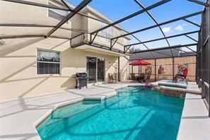 Une piscine avec un patio couvert, un barbecue et des meubles d’extérieur.