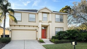 A two-story house with a garage, a red front door, and a mailbox. - Henley Haven 6 Bedroom Villa by RedAwning (Davenport)
