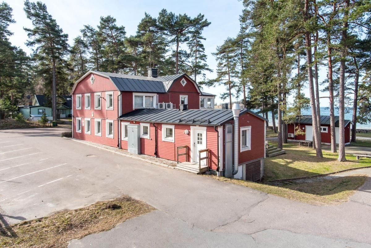 En röd byggnad med ett tak av metall, omgiven av träd och en parkeringsplats.