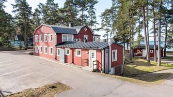 En röd byggnad med ett tak av metall, omgiven av träd och en parkeringsplats.