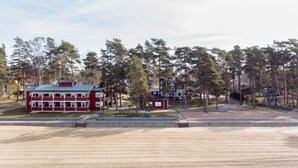 A beach with a red building in the background. - Varamons vandrarhem (Motala)