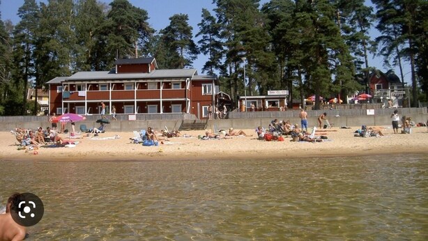 A beach with a building in the background. - Varamons vandrarhem (Motala)