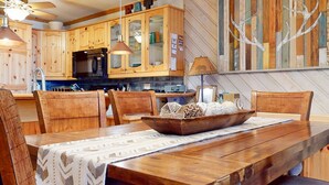 A wooden dining table with a woven centerpiece, surrounded by wooden chairs.