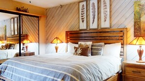 A bedroom with a large bed, wooden headboard, and two bedside tables with lamps.