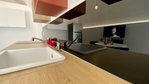 Una cocina moderna con dos fregaderos, una encimera de madera y un televisor montado en la pared.