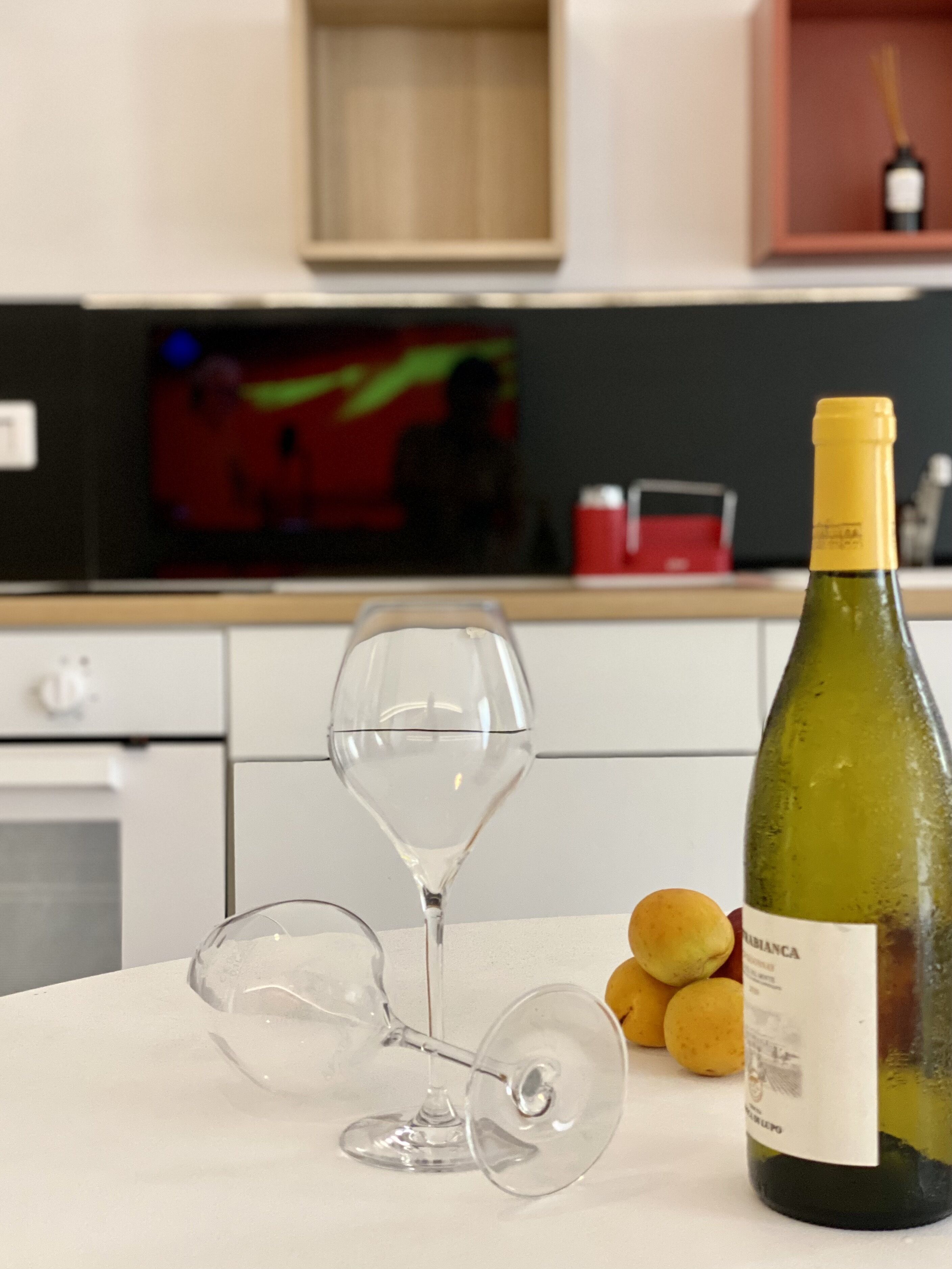 A kitchen with a wine bottle and two wine glasses on a table.