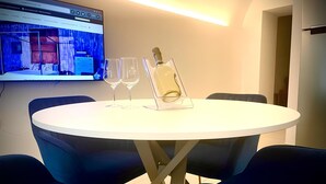 Una sala de conferencias con una mesa redonda, cuatro sillas, una pantalla que muestra una página web y dos copas de vino.