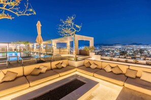 A rooftop lounge with a pool, seating area, and a view of the city at night. - Casa de Cactus | Downtown Cabo Penthouse Rental (Cabo San Lucas)