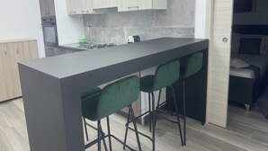 Et moderne køkken med en central ø, barstole og udsigt til et soveværelse.