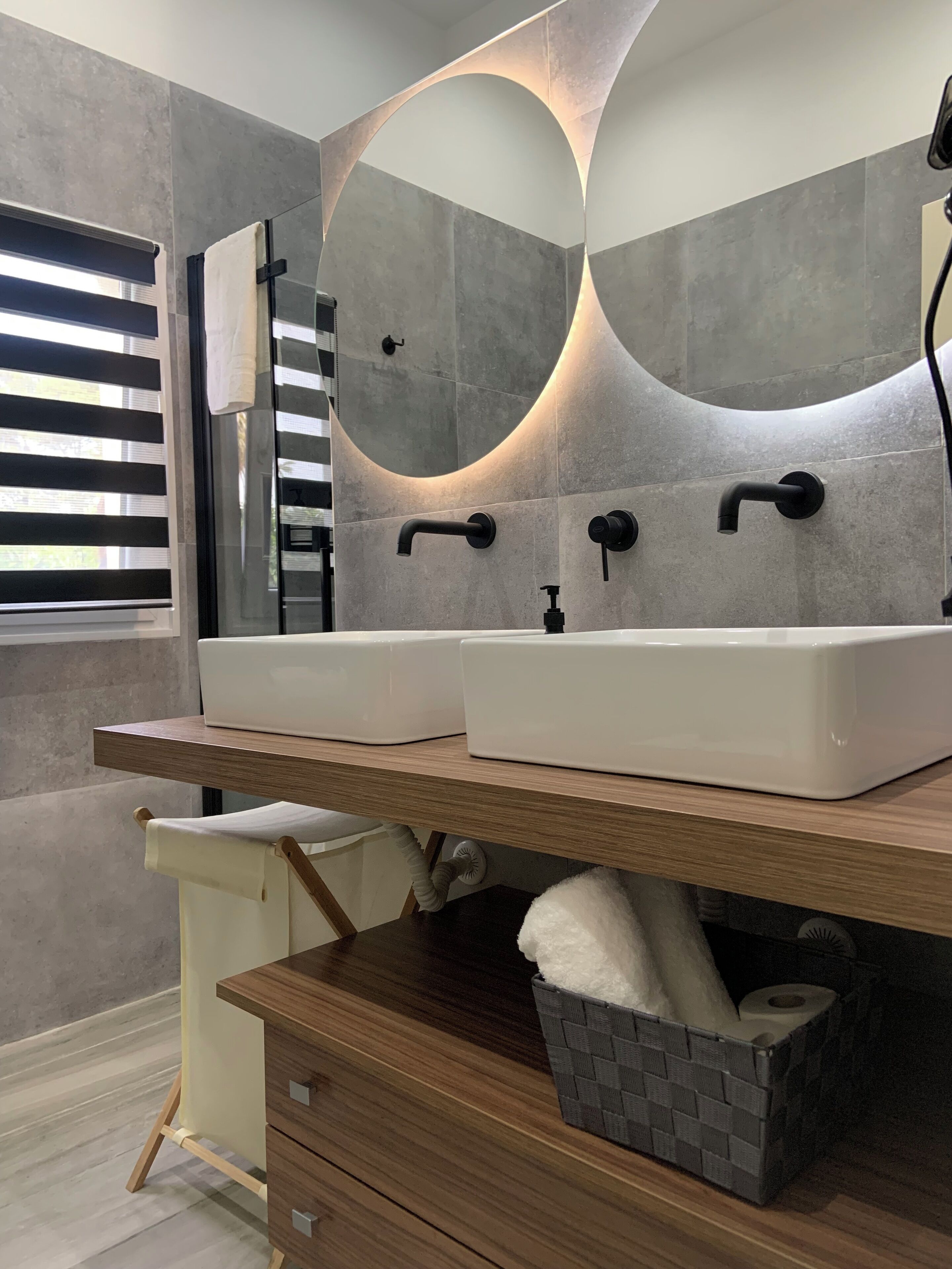 A modern bathroom with two sinks, a large mirror, and a towel rack.