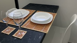 Et spisebord med tallerkener, glas og udsigt til en have fra vinduet.