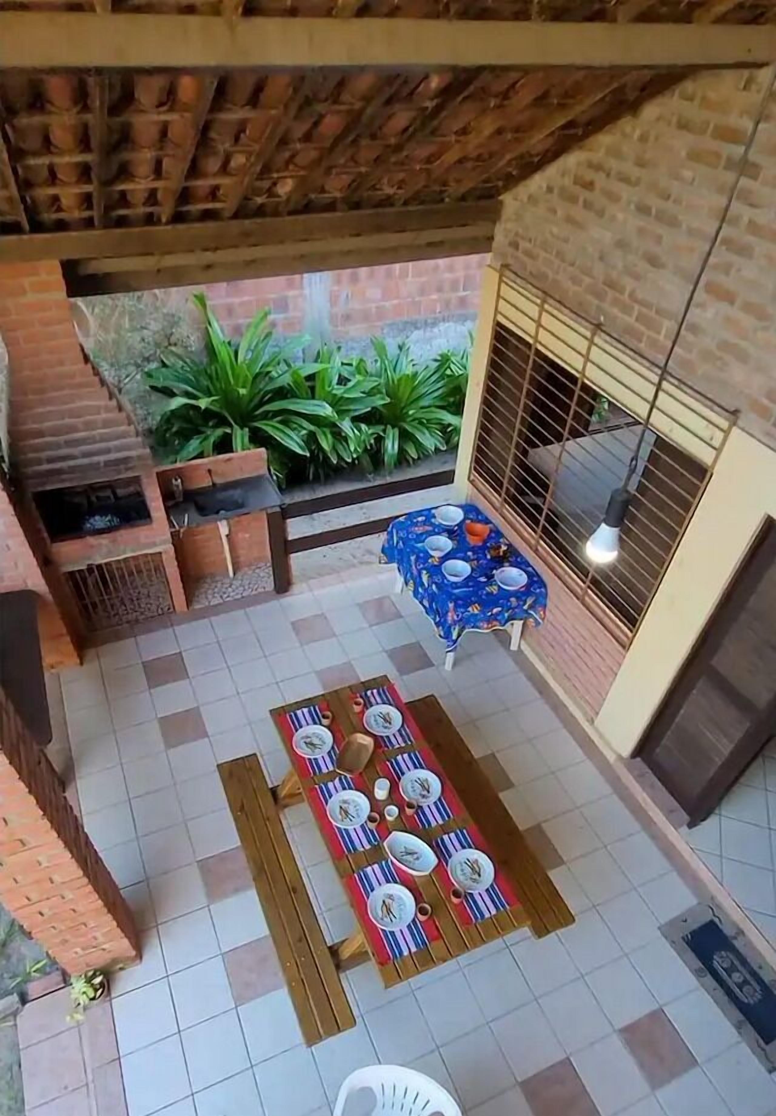 An outdoor patio with a brick wall, a wooden table set for dining, and a grill area.