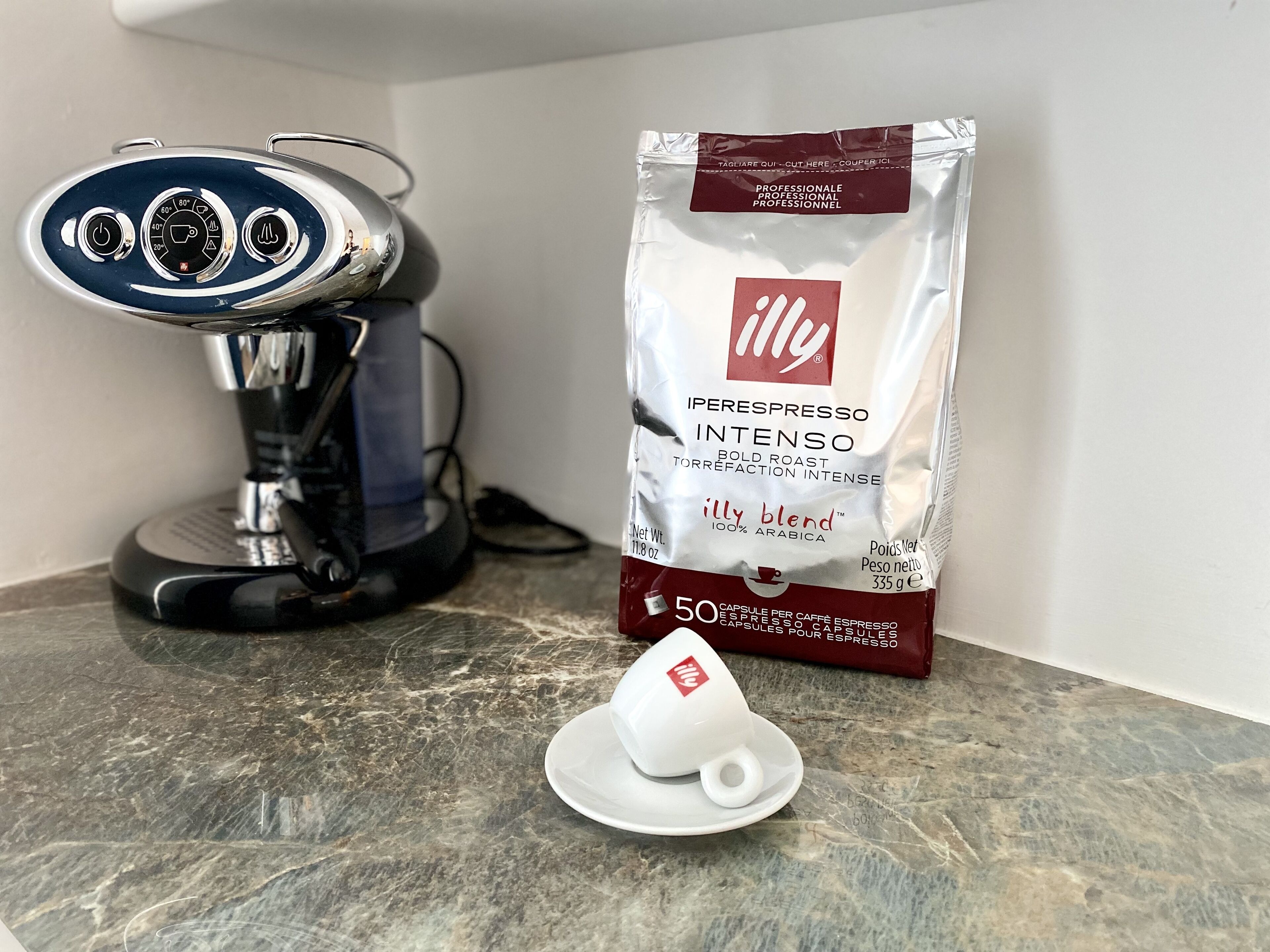 A coffee machine and a bag of Illy espresso coffee on a marble countertop.