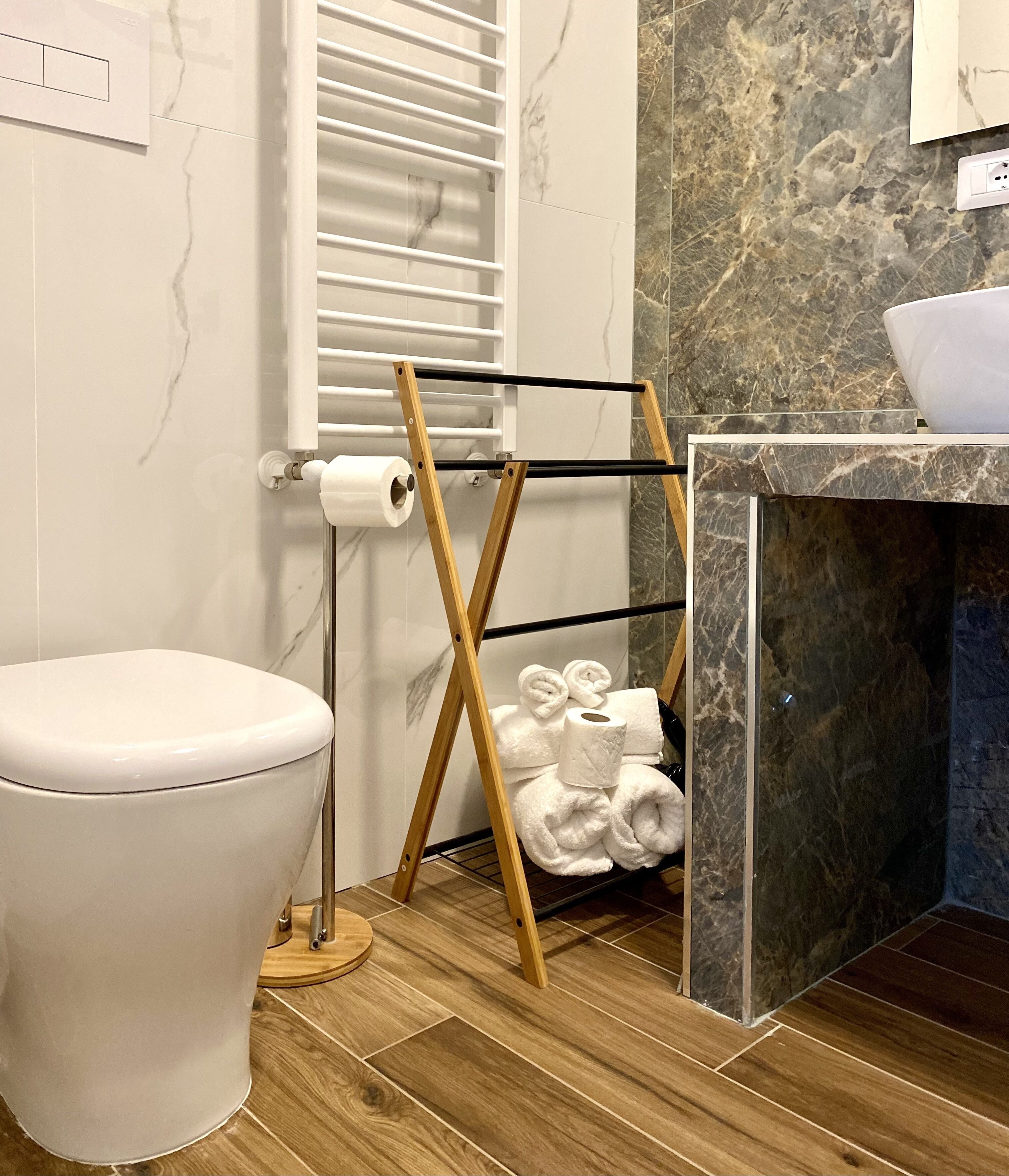 A modern bathroom with a toilet, a towel rack, and a marble sink.