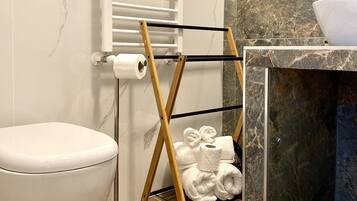 A modern bathroom with a toilet, a towel rack, and a marble sink.