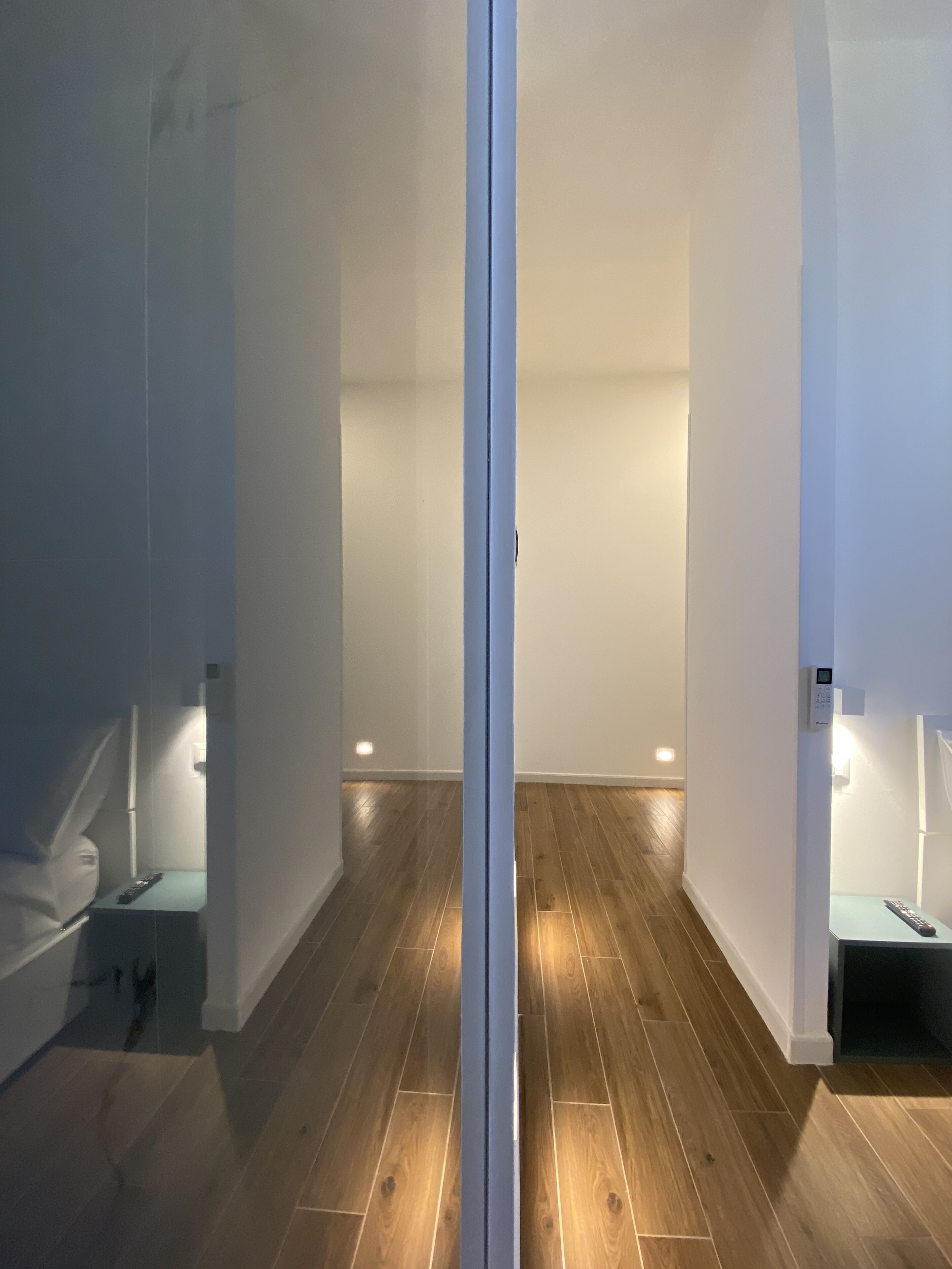 A hallway with wooden flooring, white walls, and a central door.