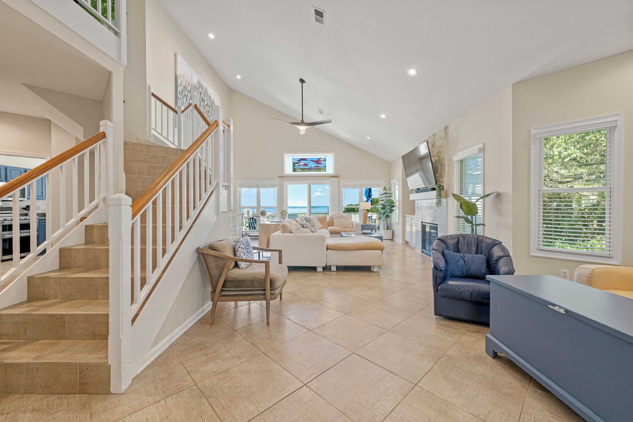 A spacious living area with a staircase, a sofa set, a television, and a view of the outdoors.