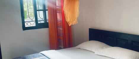 Una cama con colcha azul y blanca, almohadas blancas y un dosel naranja.