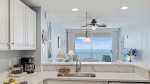 A kitchen with a view of the ocean, a ceiling fan, and a modern design. - Stunning Oceanfront Condo! Sleeps 8, Modern Appliances, Majestic (Panama City Beach)