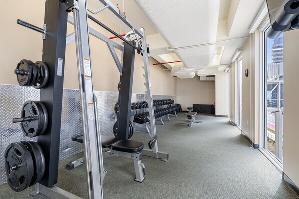 A gym with weightlifting equipment, benches, and dumbbells.