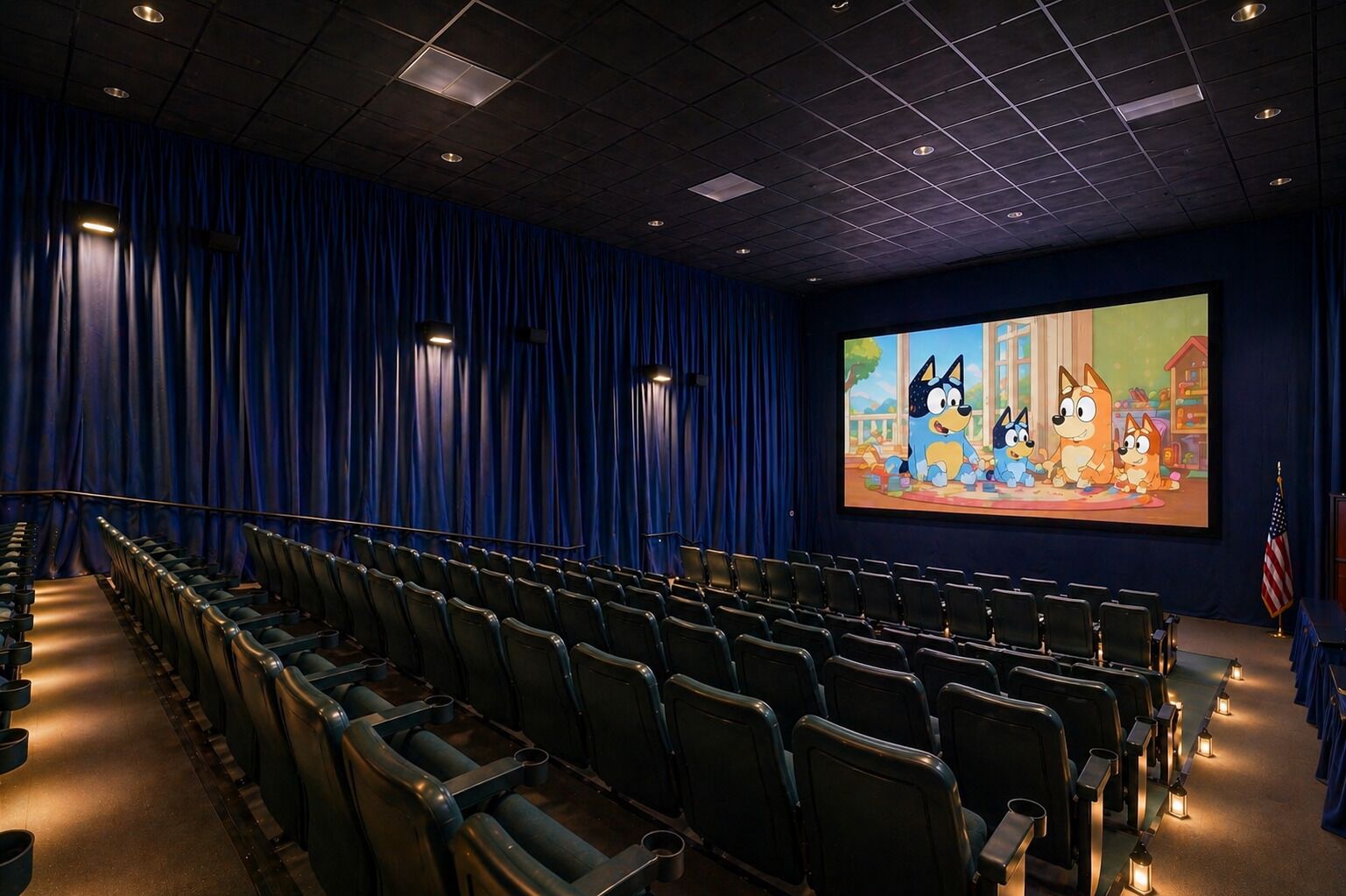 Ein Kino mit Reihen von Sitzplätzen, einer großen Leinwand und einem blauen Vorhang als Hintergrund.