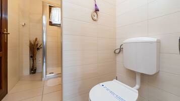 A bathroom with a toilet, a shower, and a sink.