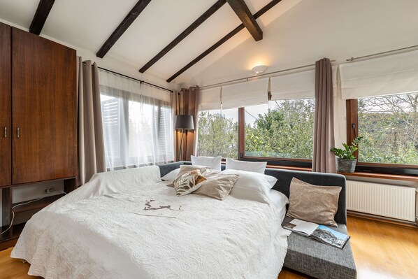 A bedroom with a large bed, wooden wardrobe, and a view of greenery through the window. - B&B Villa Sumrak Plitvica (Plitvicka Jezera)