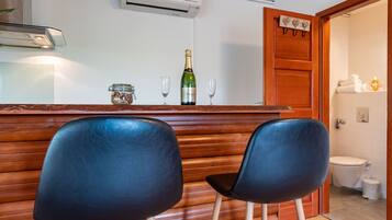 Un área de bar con dos sillas negras, una botella de Veuve Gin y dos vasos sobre una barra de madera.