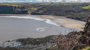 Un paysage côtier avec des falaises, une plage et un ciel dégagé.